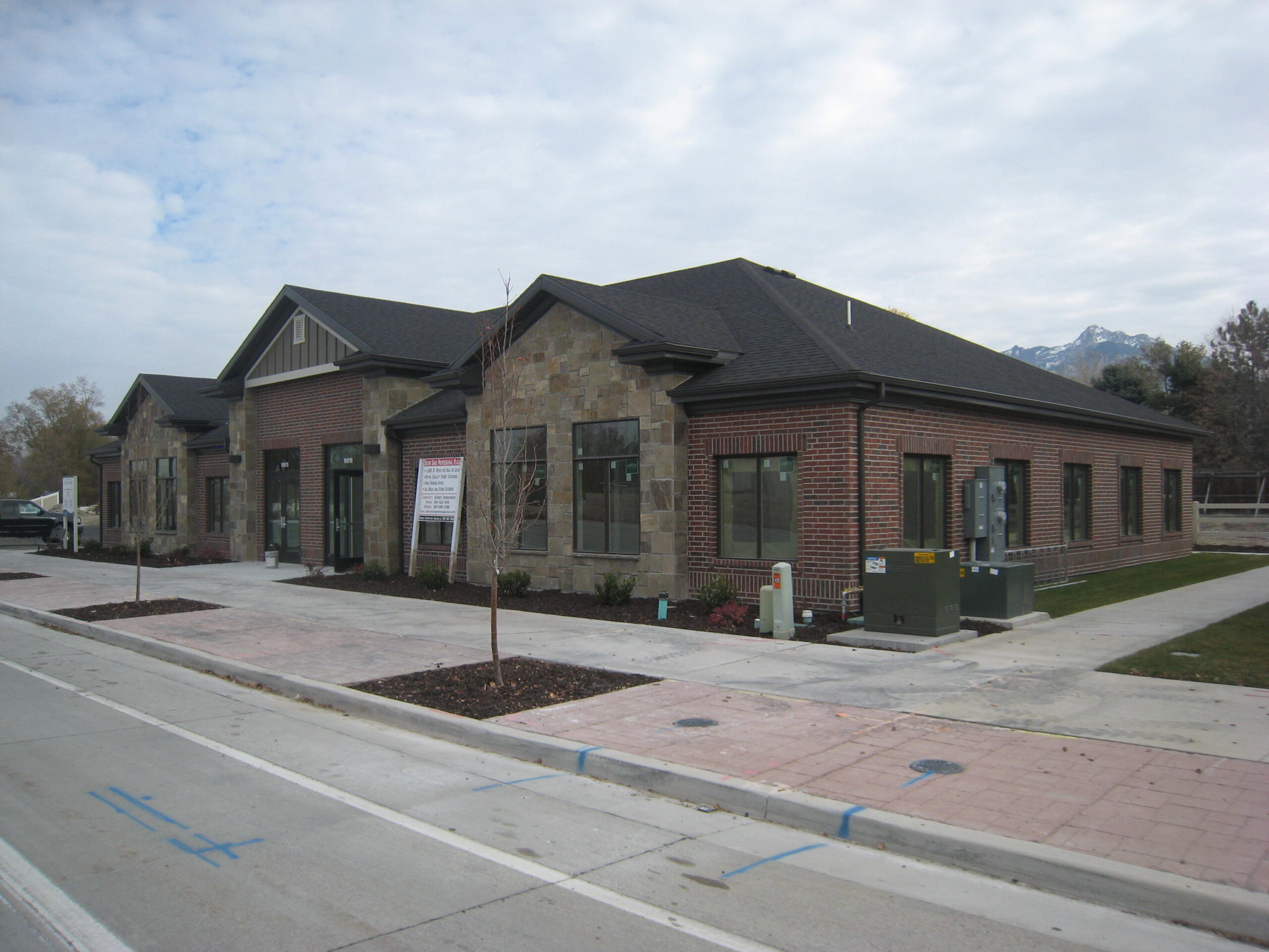 Newly constructed single-story building with a mix of stone and brick exterior, featuring large windows and landscaped surroundings.