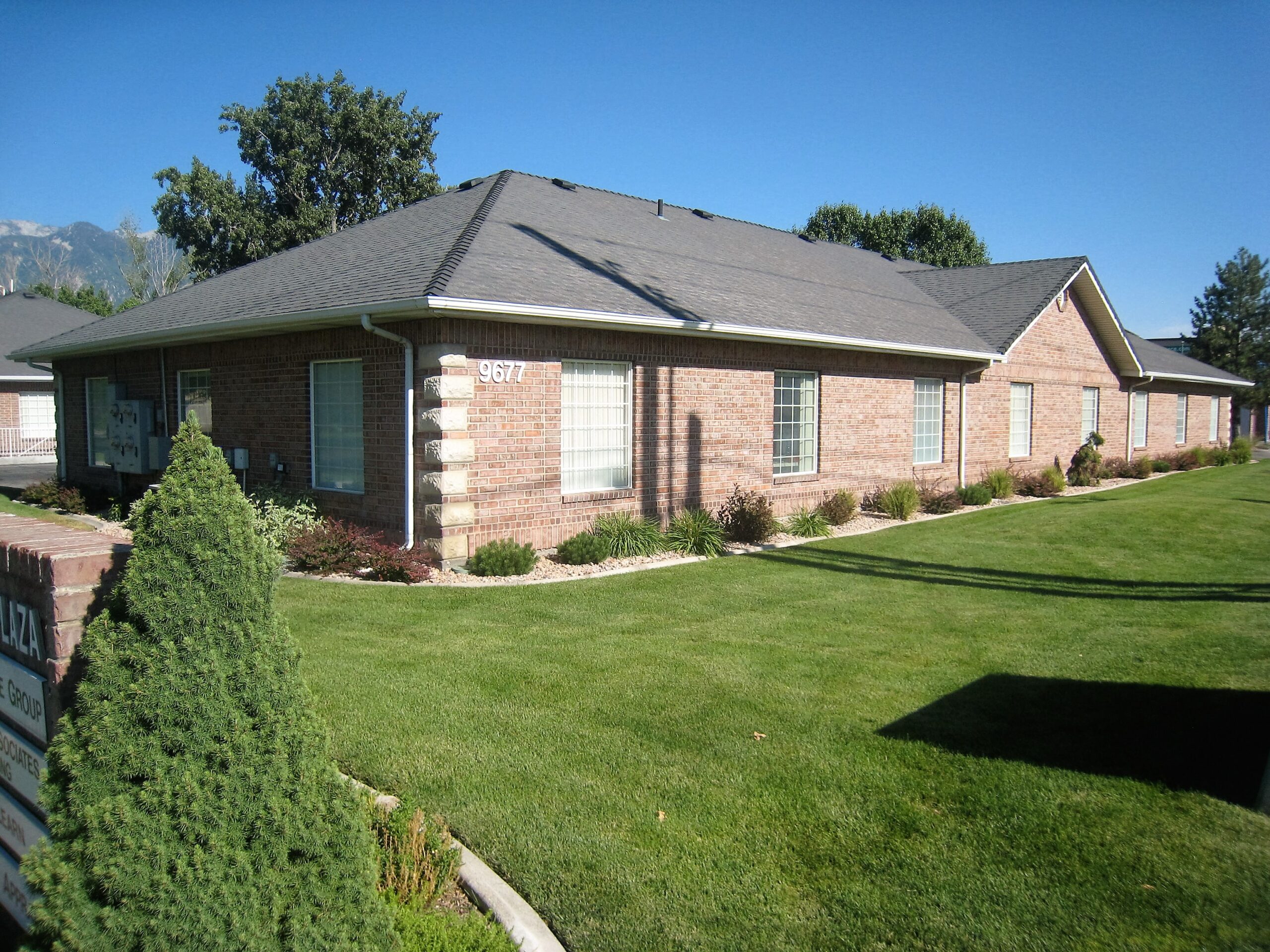 Single-story brick building with neat landscaping and a well-maintained lawn. The number "9677" is visible, indicating the location's address.