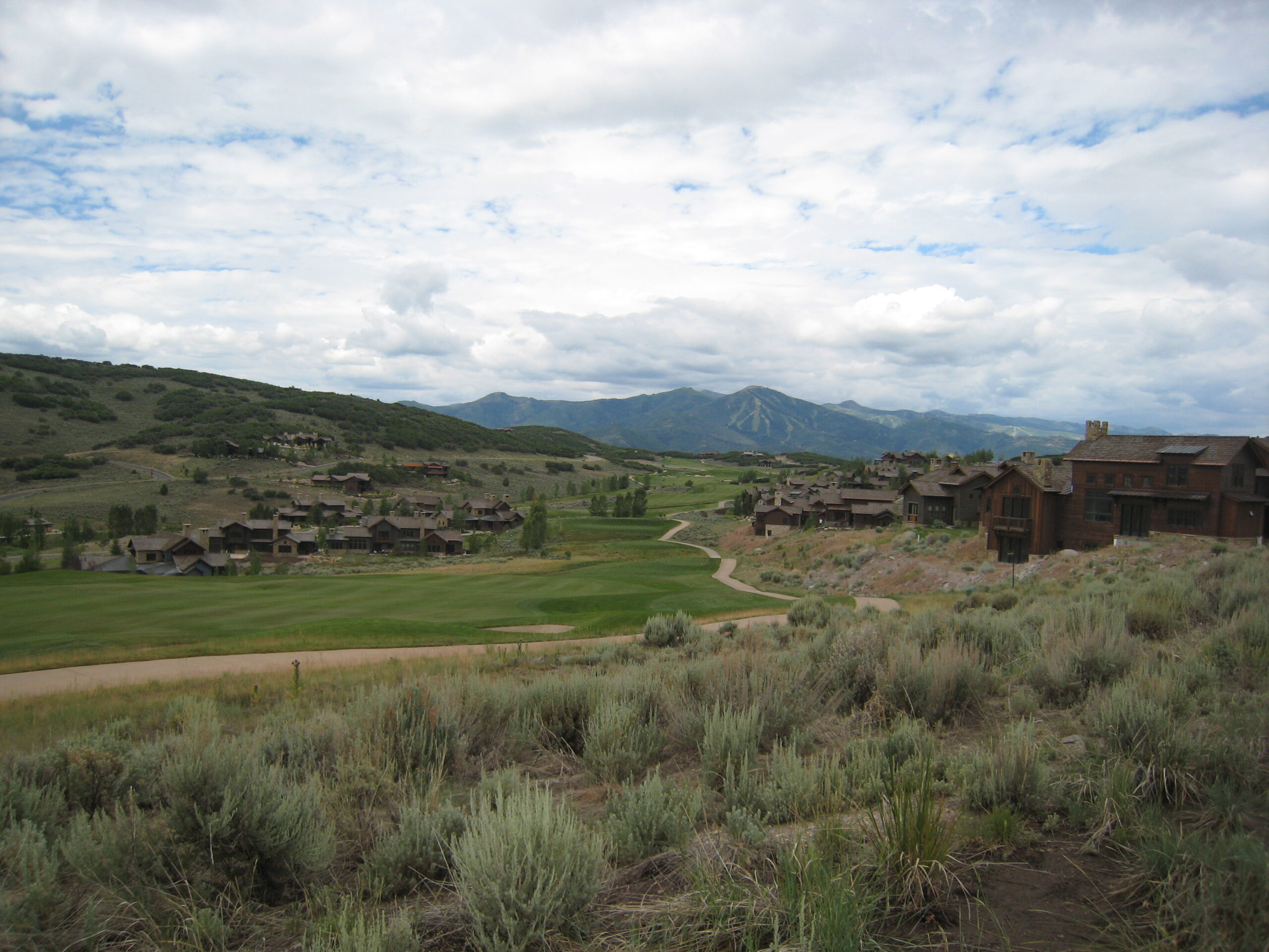 Scenic view of a sprawling landscape featuring modern homes set against rolling hills and mountains, under a partly cloudy sky. This image highlights the tranquility and natural beauty of outdoor living.